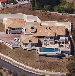 Górny widok na nowy dom Safaree Samuela z dużą zieloną ziemią i niebieskim basenem