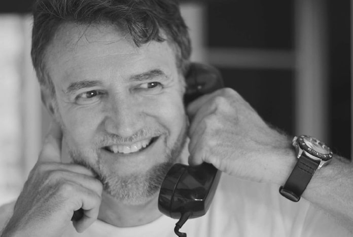 A black and white picture of Joe Chrest holding telephone.