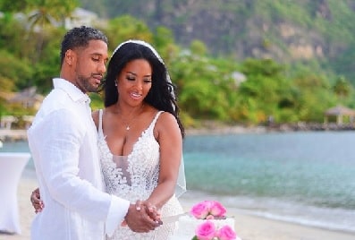 Marc Daly and Kenya Moore holding their hands while posing on their wedding day.