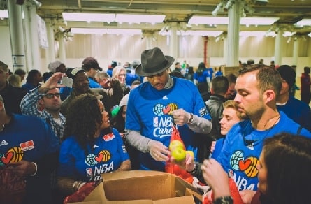 Carmelo Anthony in blue shirt helping in his own Carmelo Anthony Foundation.