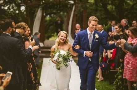 Sara Murray on her white wedding gown while holding hands with Garrett Haake. 