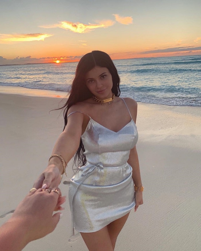 Kylie on the beach in a white satin dress.