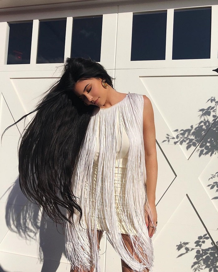 Kylie outdoors in a fringed white dress.