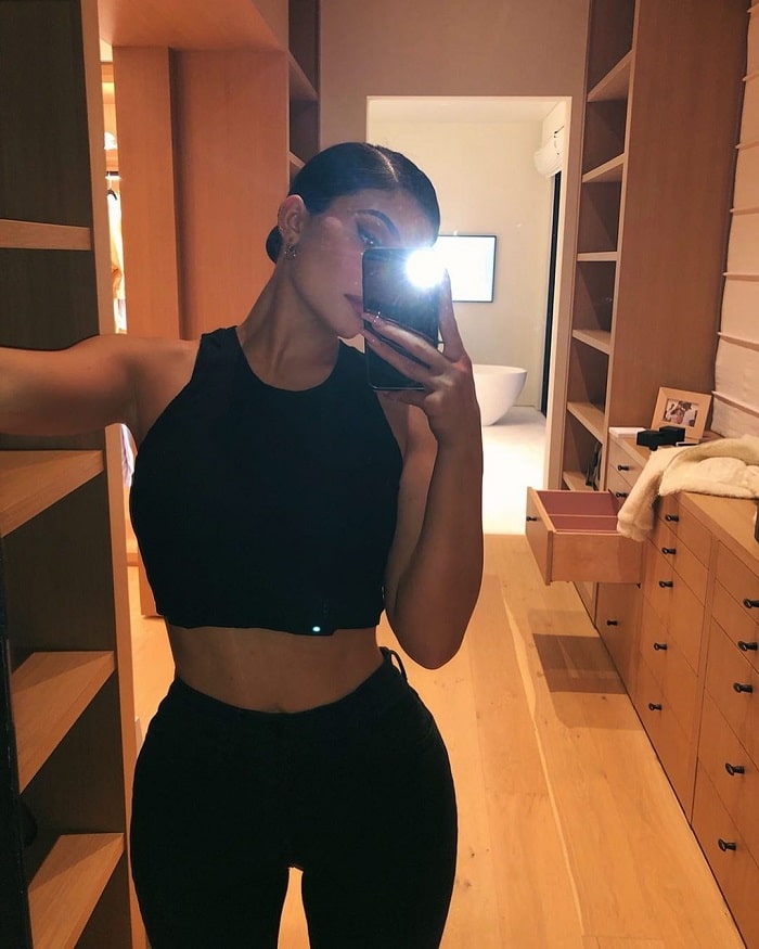 Kylie in a black crop top and black pants.