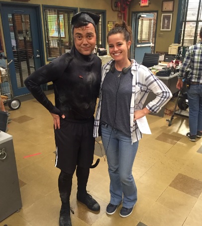 Carly Hallam taking a picture in a set of Brooklyn99.