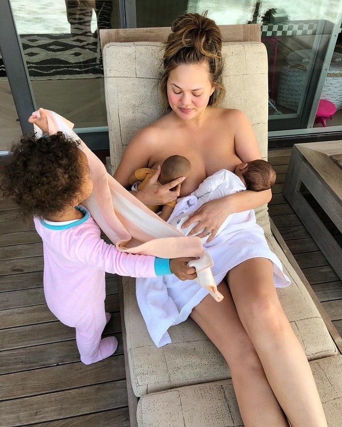 Chrissy breastfeding her baby and her daughters doll