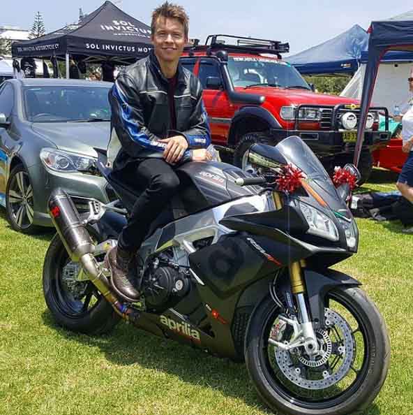 Todd Lasance poses for a picture in black colored Aprilia super bike.