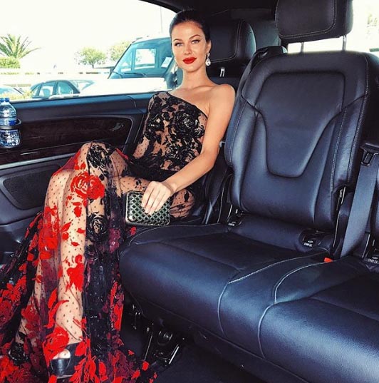 Jenny Watwood taking a picture inside a lavish car.