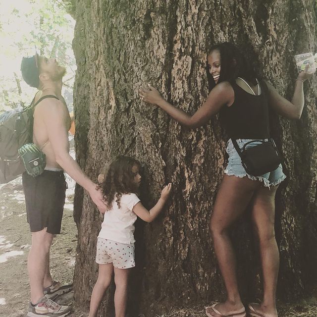 Nick James, Tika Sumpter, and their daughter Ellen-Lauren hugging a tree