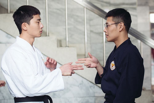 On the left Park Seo Joon in his white martial arts dress and on left Kang Ha Neul in his navy martial arts dress