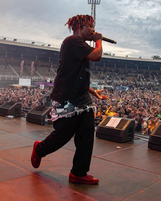 Juice Wrld wearing black tee and black jogger and a red shoes.