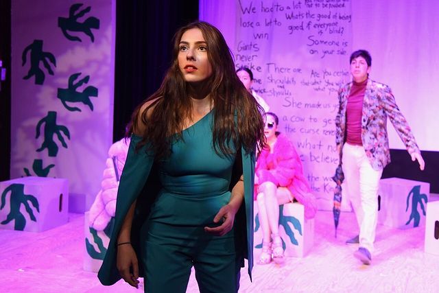 Bella Cuomo playing a drama at her school function wearing a navy blue dress