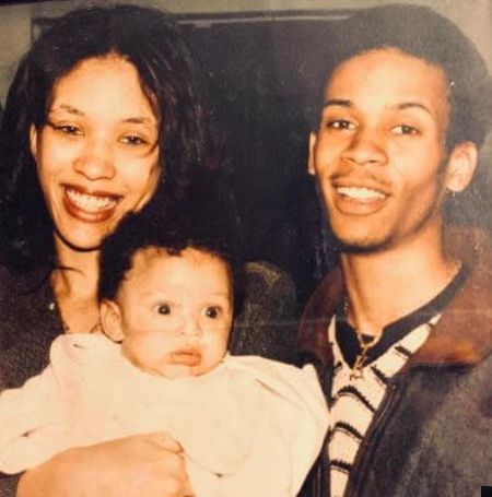 Kecalf Cunningham is wearing brown jacket with black and white mix tee, his wife is wearing black top and his daughter wearing white baby clothes.