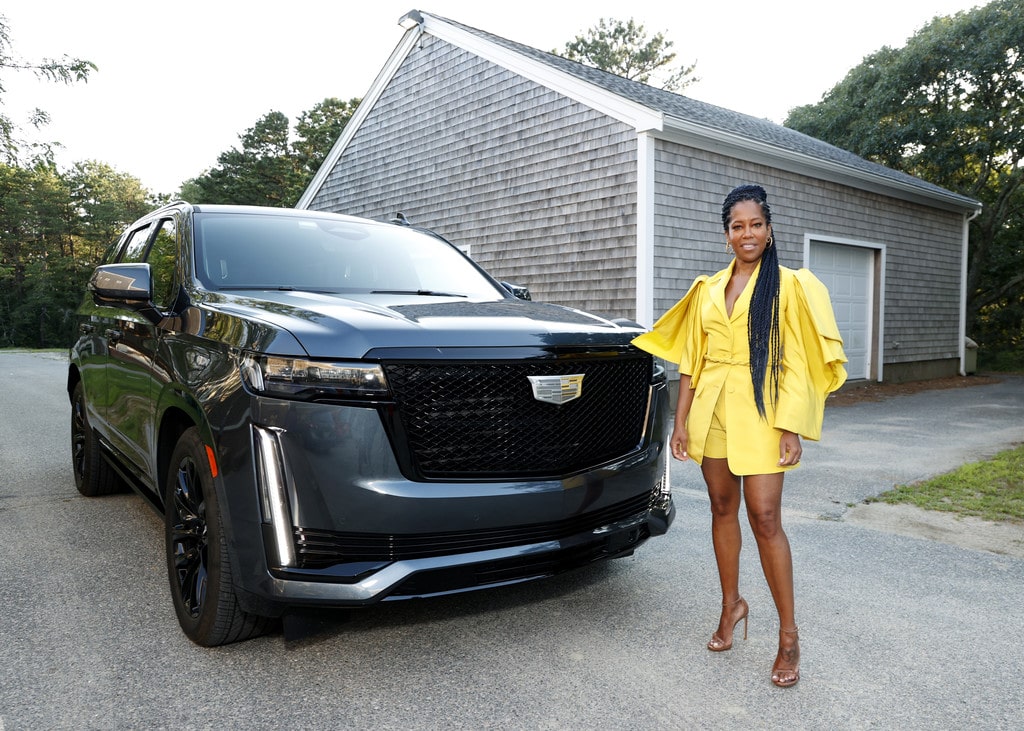 Regina King showing off her Cadillac Escalade wearing a yellow dress