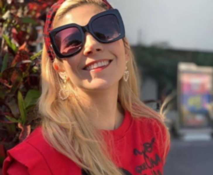 Picture of Karla Panini posing for photo smiling with black sunglass on in streets.