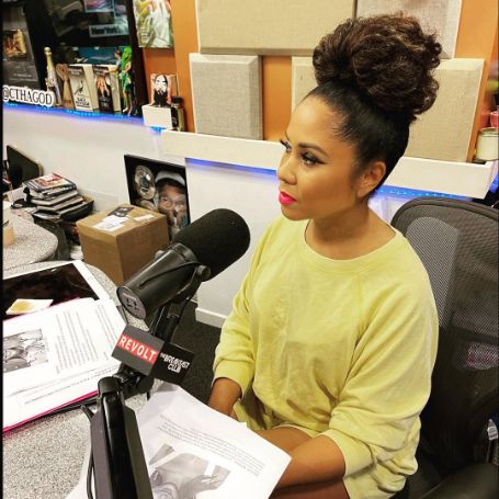 Angela Yee posing working infornt of mike. 